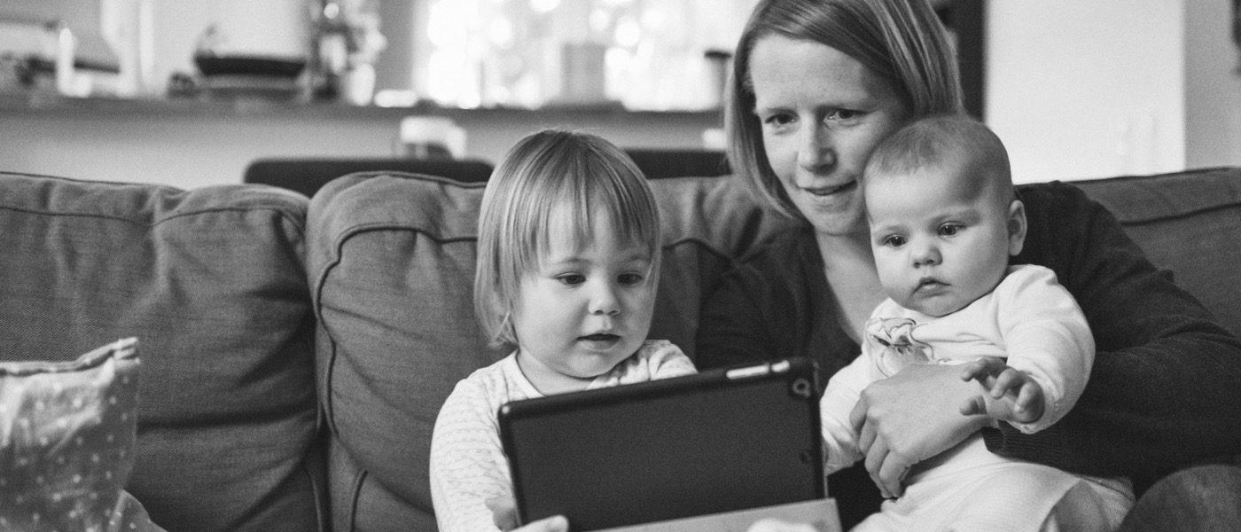 Mother working on her tablet with two of her children in hand