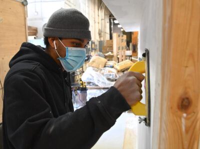 A man sands mud seams on drywall.