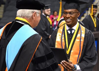 A graduate shakes hands with Dr. Keen.