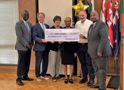 County Commissioners Charles Evans, Toni Stewart, Jimmy Keefe and Glenn Adams as well as FTCC vice president Mark Sorrells and county manager Amy Cannon pose with a large check.