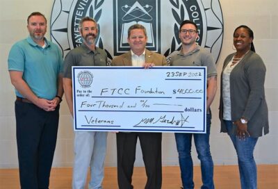  Joseph Quigley, scholarship recipient; Chris Herring, FTCC Department Chair Security Systems and Analysis; Marv Gordner, AFCEA NC Representative and FTCC Foundation Board Member; Ryan Hodgson, scholarship recipient; and Brittany Chapman, scholarship recipient, hold a giant check.