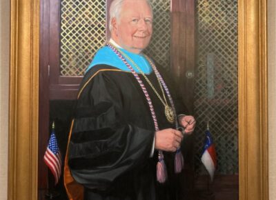 A framed oil painting portrait of Dr. Larry Keen in academic regalia.