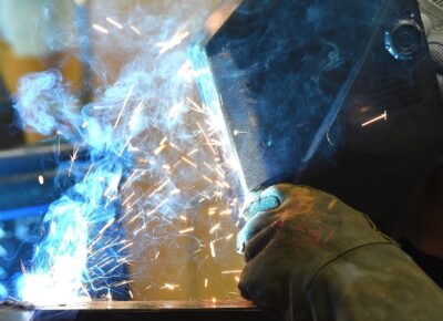 A close-up photo of a person wearing protective helmet and gloves welding metal.