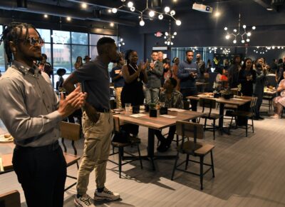 Students stand and applaud in the dining hall.