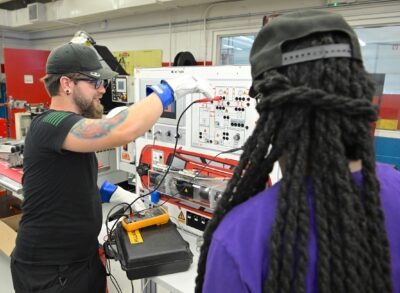 Nathan Entriken works at an electric vehicle systems training board while classmate Tiffany Bethea looks on.