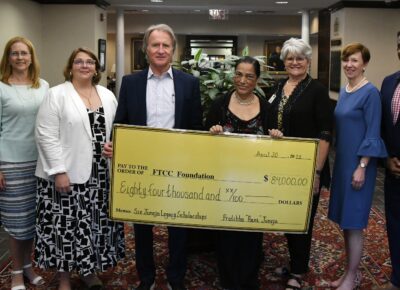 A group of people stand behind a presentation check.