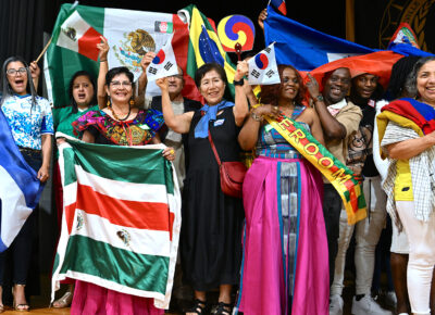 A group of people hold flags from a variety of countries.