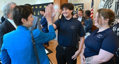 A woman and young man high-five while a young woman looks on.