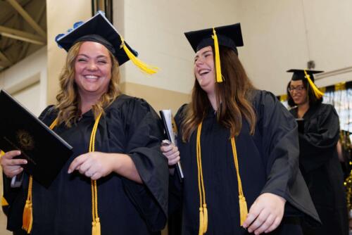 Three-graduates-grin-as-they-enter-the-Expo-Center-after-graduation
