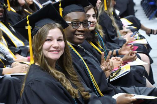 Three-graduates-smile-at-the-camera-and-one-flashes-the-peace-sign-as-they-sit-inside-the-Crown