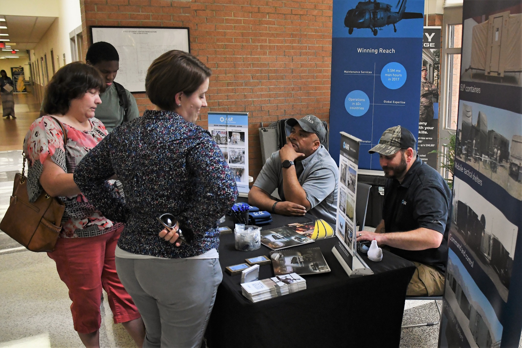 Two attendees talk with employers at a table the Expo.