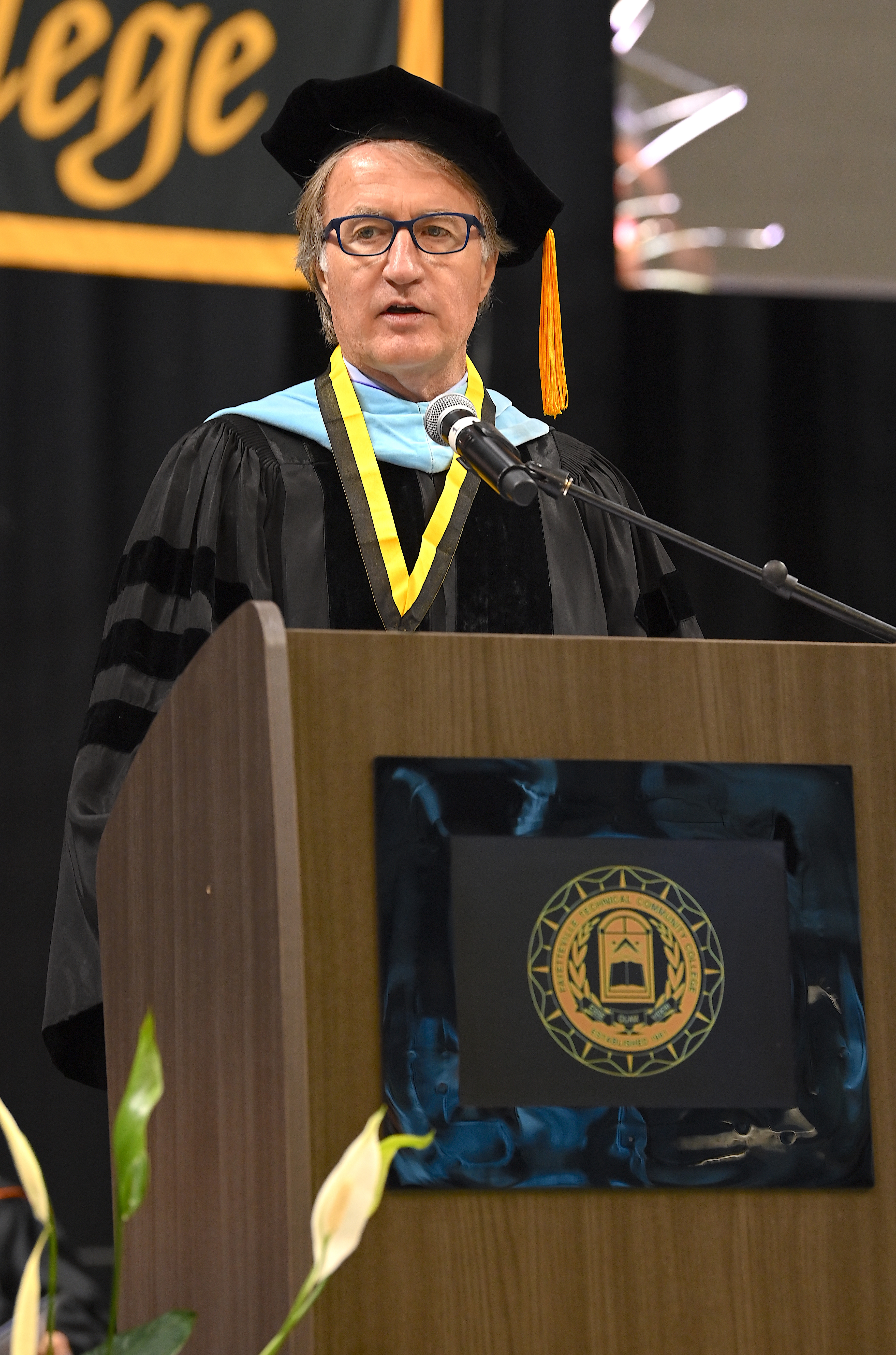 Dr. Mark Sorrels, dressed in doctoral regalia, speaks at the podium.
