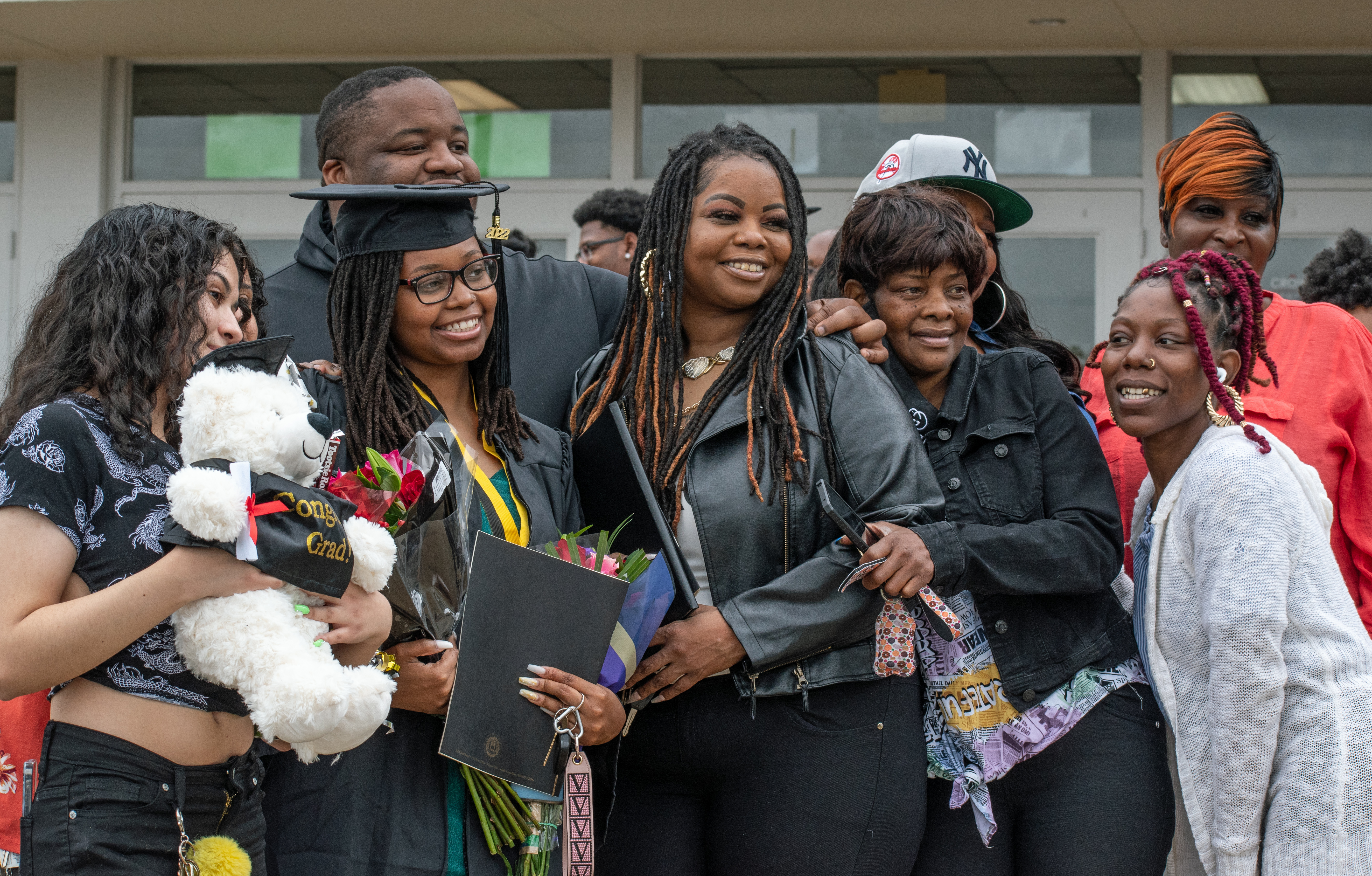 A graduate and her loved ones pose for a photo being taken by someone out of frame.