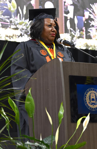 Pastor Sharon Thompson-Journigan, dressed in a cap and gown, delivers the invocation at the podium.