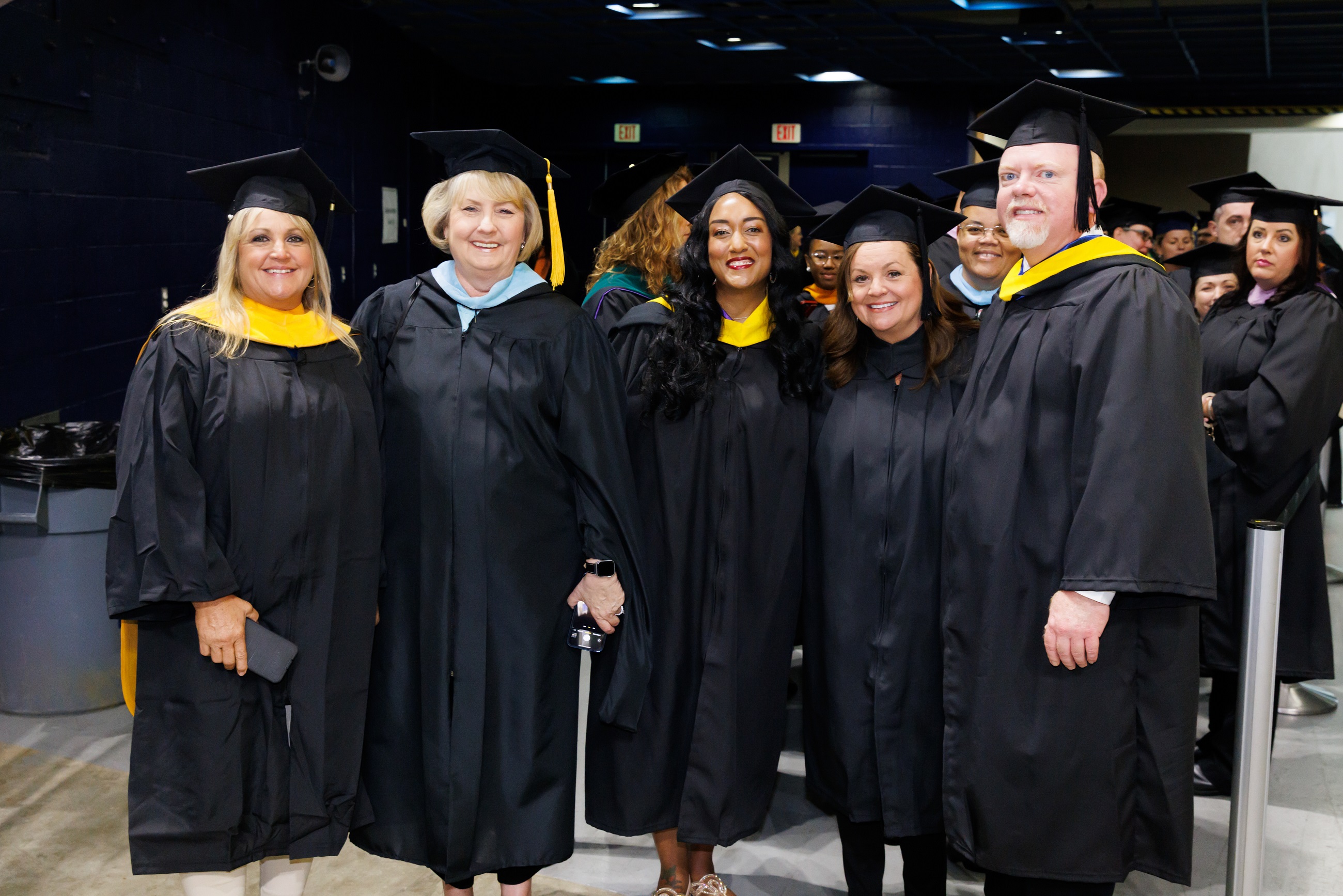 Five faculty members pose for a photo in the entrance tunnel to the Crown.