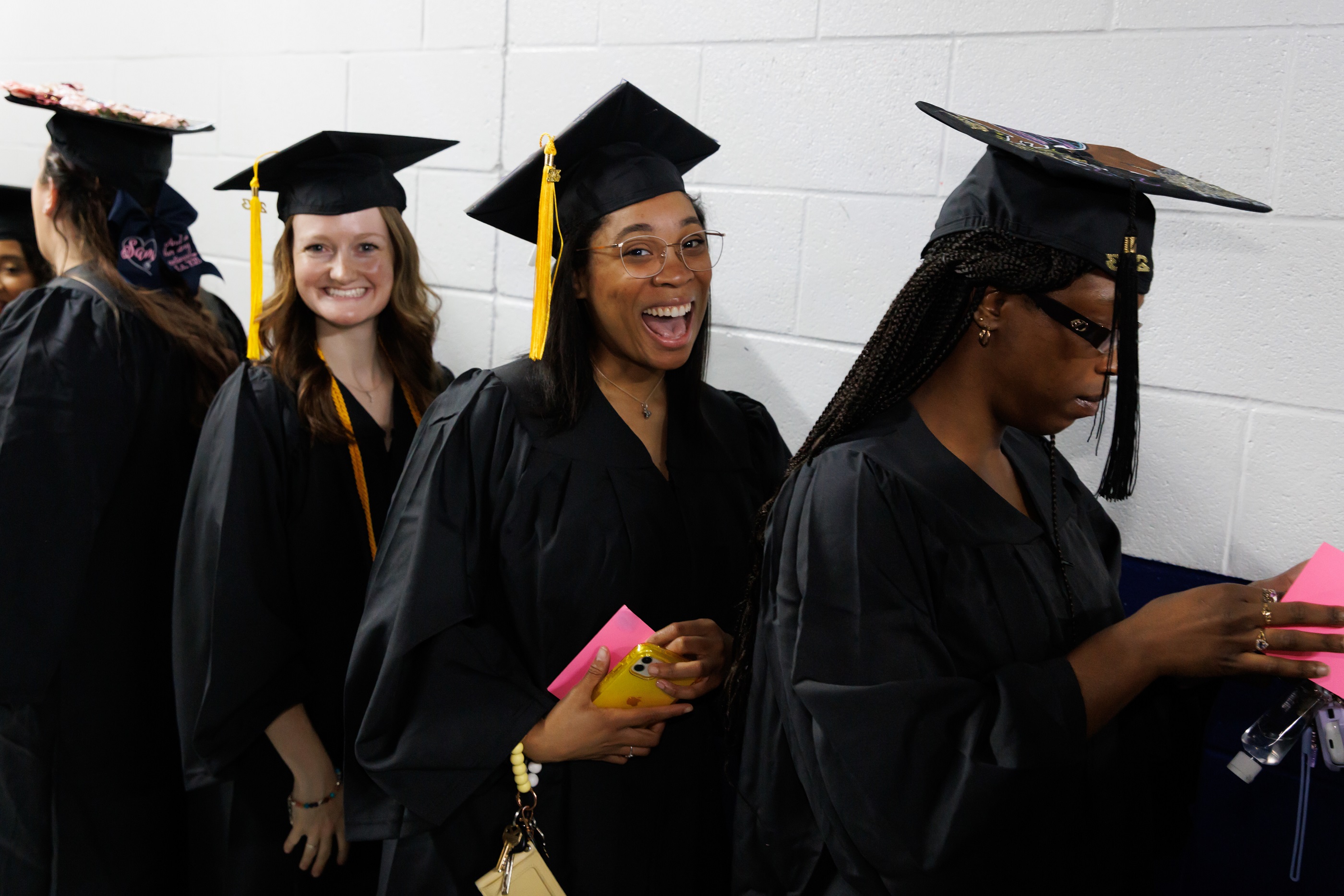 A graduate gives an open-mouth smile to the camera while waiting in line backstage at the Crown.