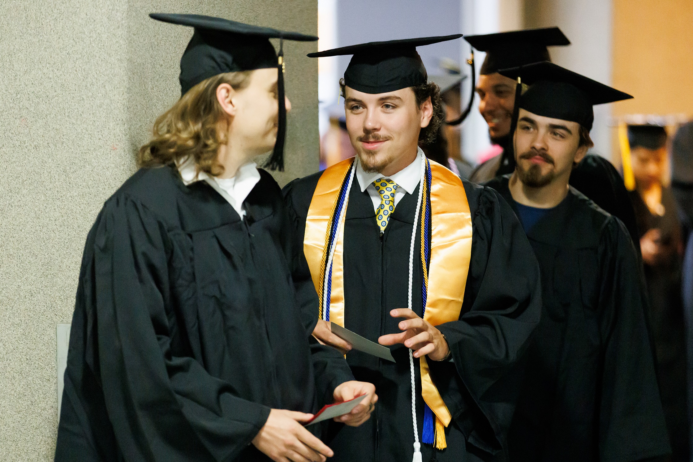 Graduates talk among themselves while waiting in line backstage at the Crown.
