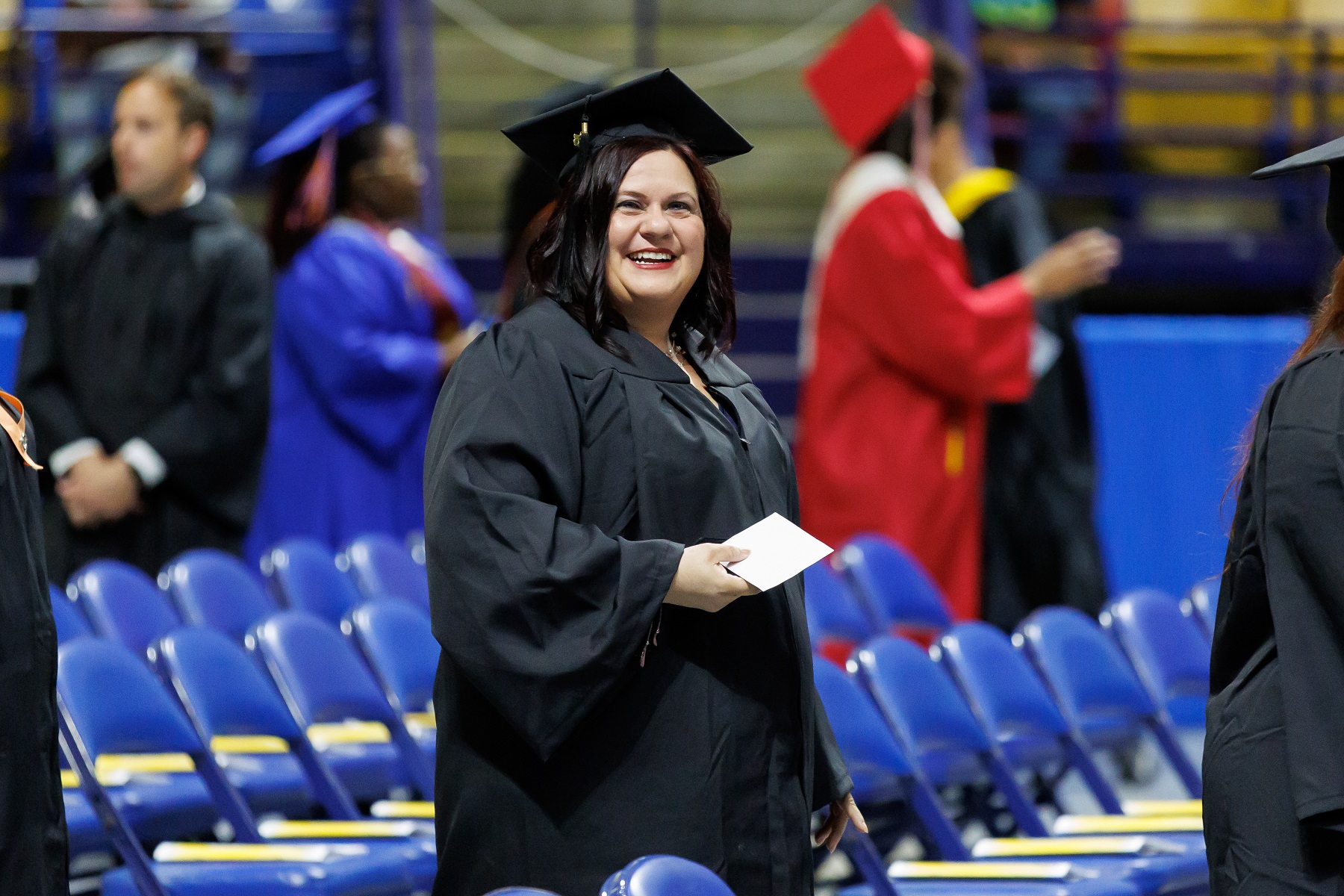 A graduate smiles as she walks in the processional line at graduation.