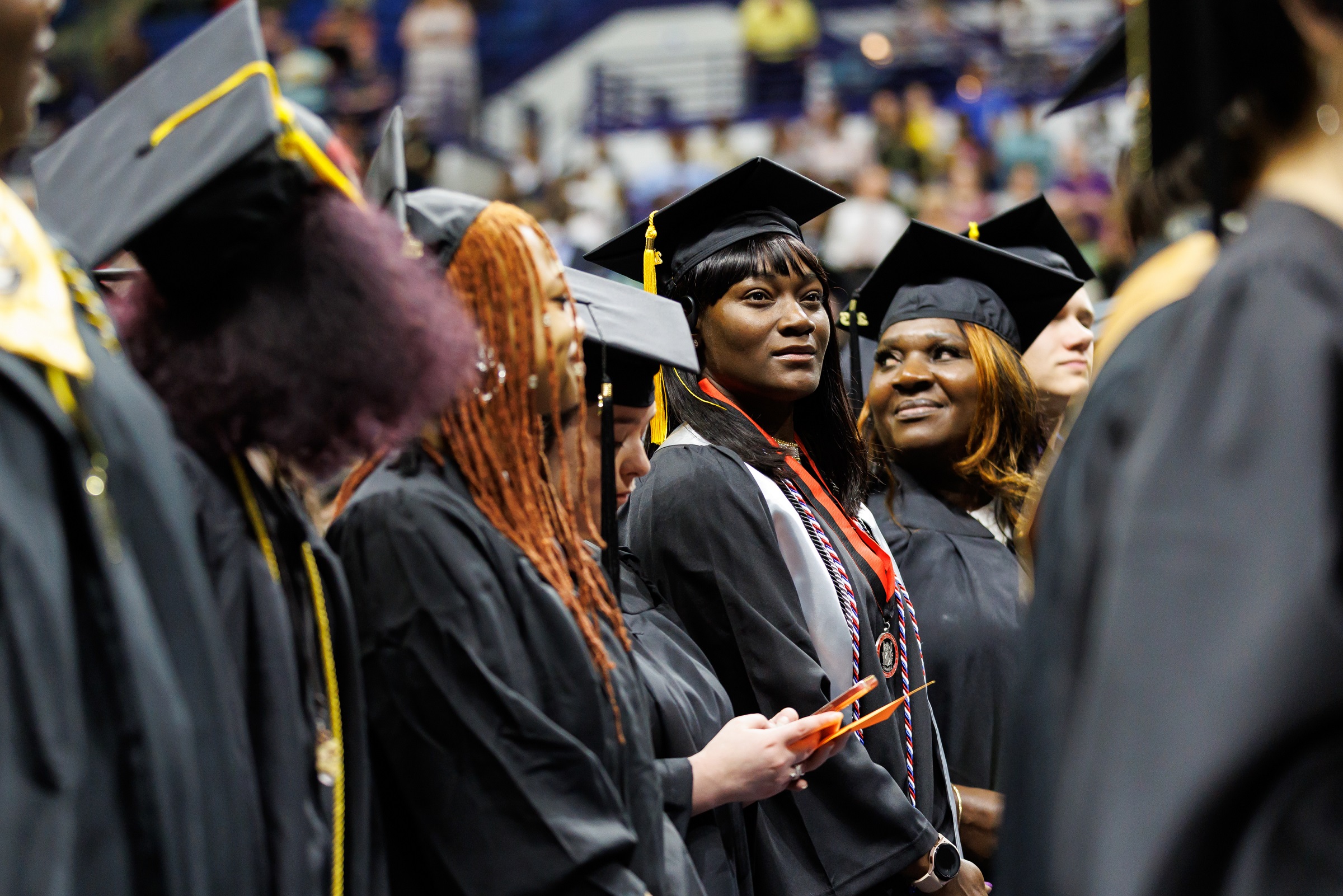 A row of graduates look up into the crowd while waiting to take their seats.