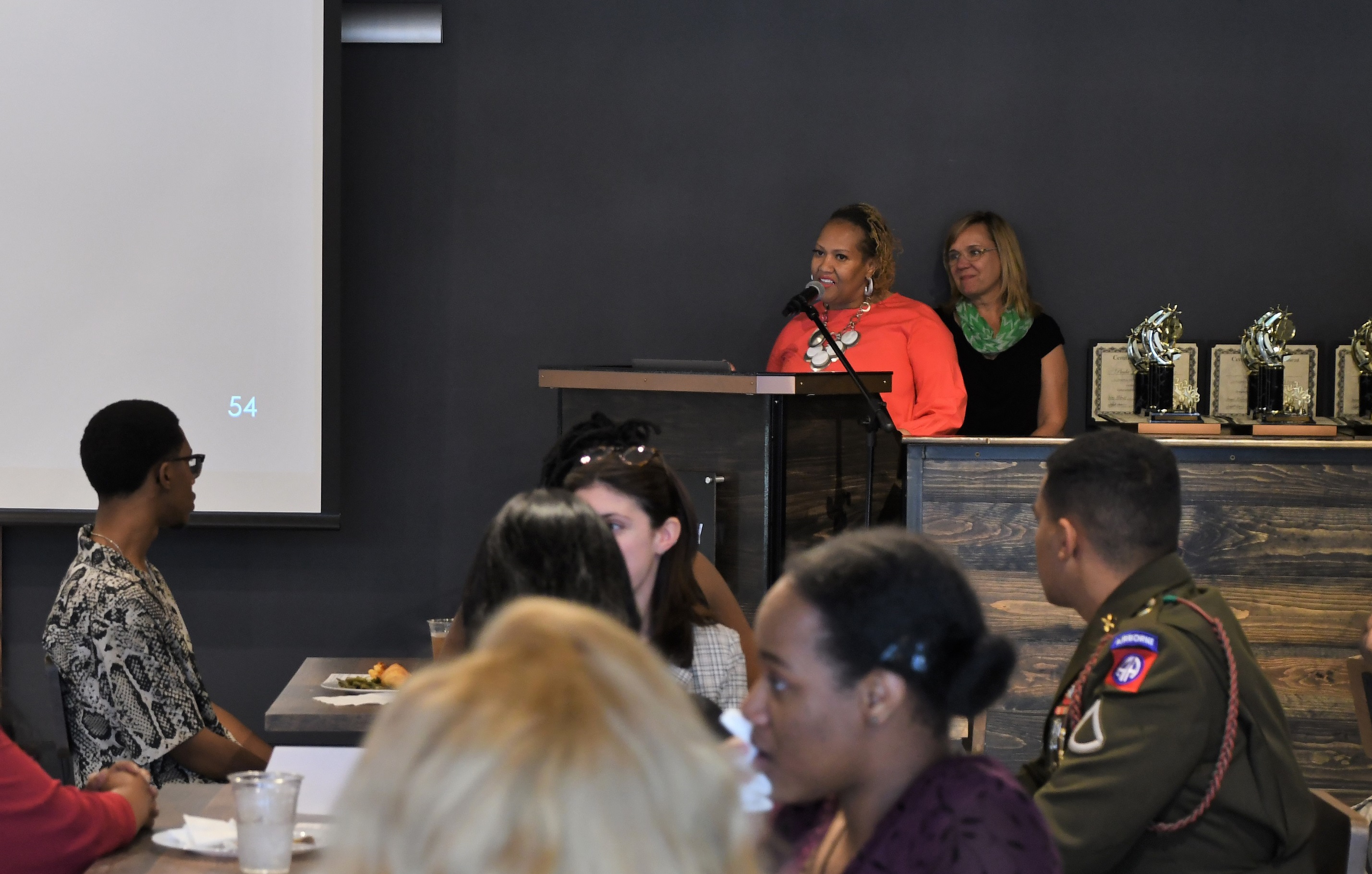 Dr. DeSandra Washington and Dr. Murtis Worth stand at the podium in front of the dining hall.