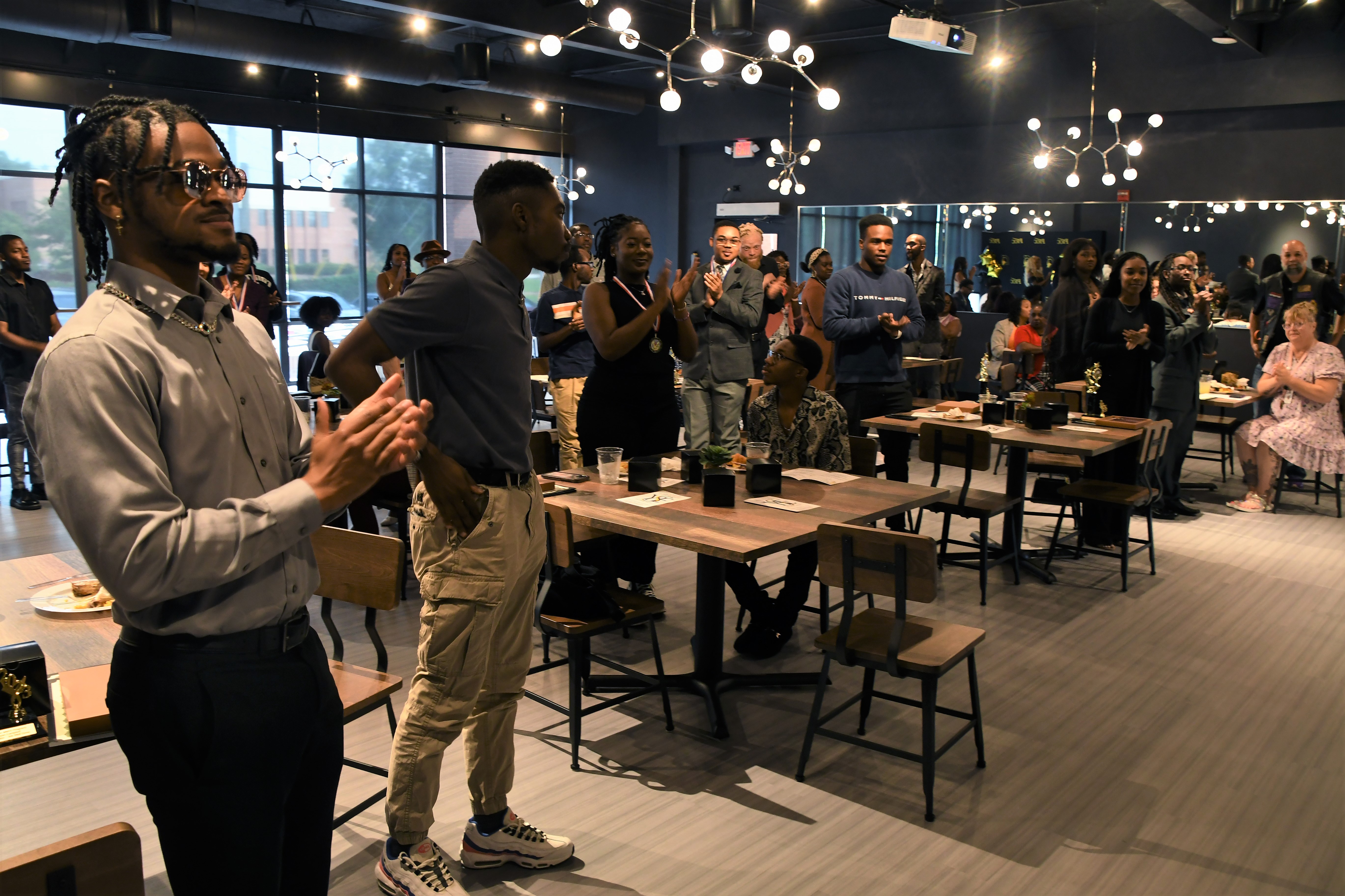 Students stand and applaud in the dining room.